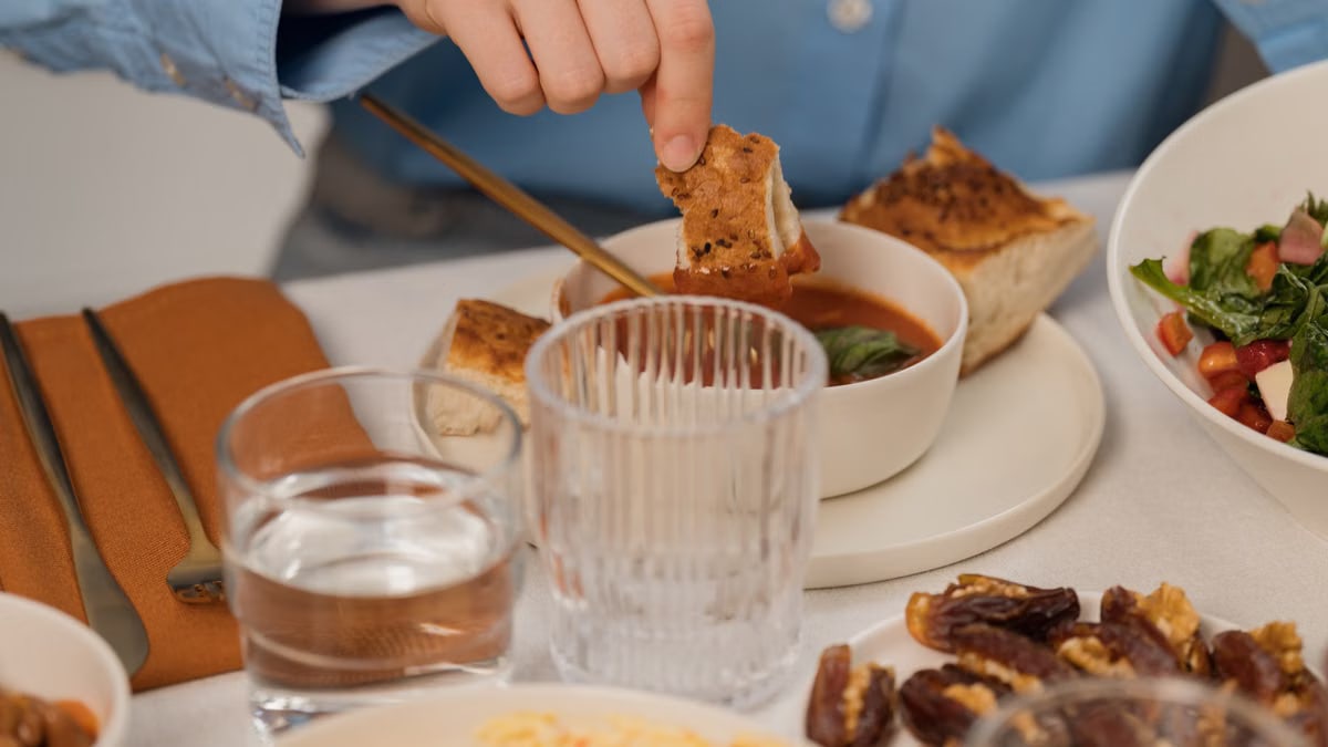 A warm dinner setup with soup, bread, salad, and glassware on a table.